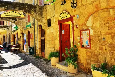 a stone building with a red door on a street at Olympos Pension in Rhodes Town