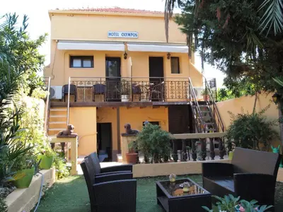 a house with a balcony and chairs in the yard at Olympos Pension in Rhodes Town