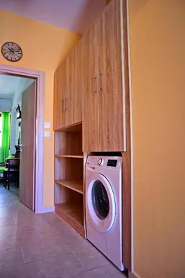 a laundry room with a washing machine and wooden cabinets at Olympos Pension in Rhodes Town