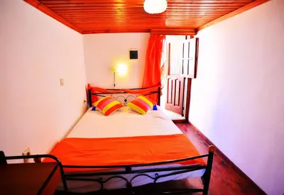 a small bedroom with a bed with colorful pillows at Olympos Pension in Rhodes Town
