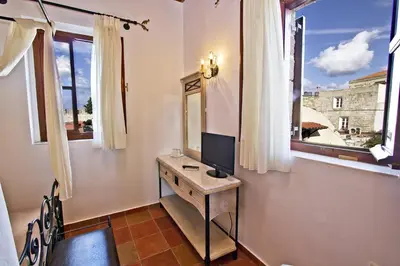 a room with a desk with a television and windows at Camelot Traditional & Classic Hotel in Rhodes Town