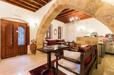 a living room with a table and a kitchen at Camelot Traditional & Classic Hotel in Rhodes Town