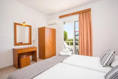 a bedroom with two beds and a mirror and a window at Sam's Faliraki in Faliraki