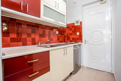 a kitchen with a sink and red tiles on the wall at Yianna Studios in Faliraki