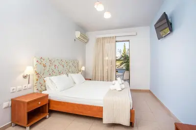 a bedroom with a white bed and a tv at Yianna Studios in Faliraki
