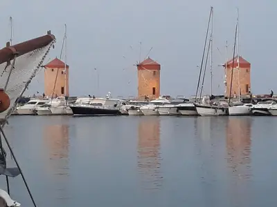 a group of boats docked in a harbor with a windmill at Iatridis Studios Faliraki in Faliraki