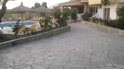 a stone walkway next to a house with a swimming pool at Summer Days in Faliraki