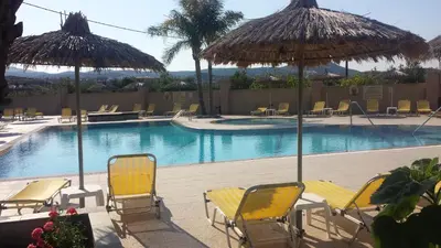 a swimming pool with yellow chairs and umbrellas at Summer Days in Faliraki