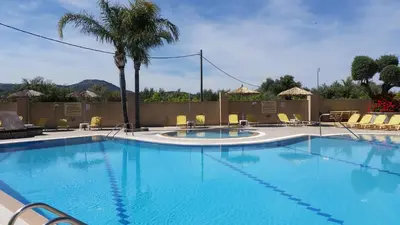 a large swimming pool with chairs and a palm tree at Summer Days in Faliraki