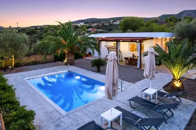 a pool with chairs and umbrellas in a backyard at Evgenias Olive House in Kalathos