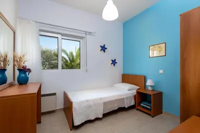 a bedroom with a bed with blue walls and a window at Evgenias Olive House in Kalathos