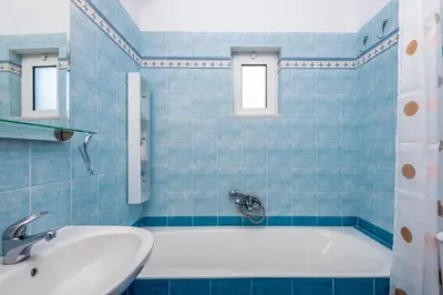 a blue tiled bathroom with a tub and a sink at Evgenias Olive House in Kalathos