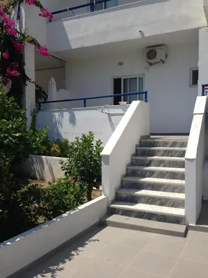 a staircase leading up to a white house with pink flowers at Corafili Holiday Suites in Kiotari