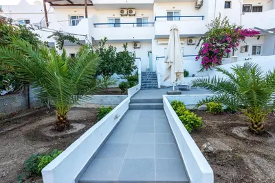 a walkway in front of a building with palm trees at Corafili Holiday Suites in Kiotari