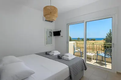 a white bedroom with a bed and a balcony at Olive Tree House in Gennadi