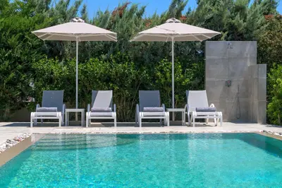 a group of chairs and umbrellas next to a pool at Olive Tree House in Gennadi
