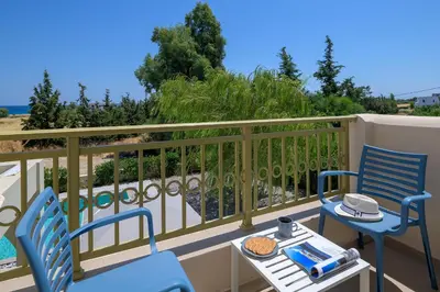 a balcony with two blue chairs and a table at Olive Tree House in Gennadi