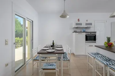 a white kitchen with a table and chairs and a counter at Olive Tree House in Gennadi