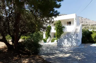 a white house with a tree in front of it at Villa Stamatis in Pefki Rhodes