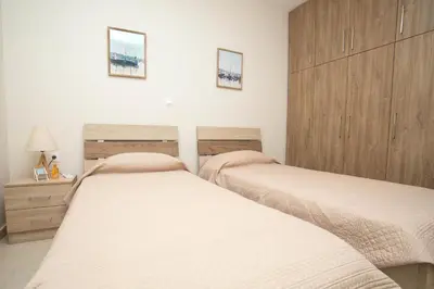 two twin beds in a bedroom with wooden cabinets at Rhodes Marine House in Rhodes Town