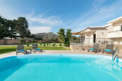 a swimming pool with chairs and a house at Sugar View Villa In Kolymbia in Kolimbia