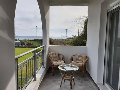 a balcony with two chairs and a table and a window at Sea Breeze Villa in Haraki