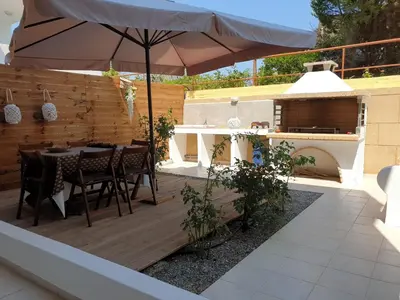 a patio with an umbrella and a table and a grill at Sea Breeze Villa in Haraki