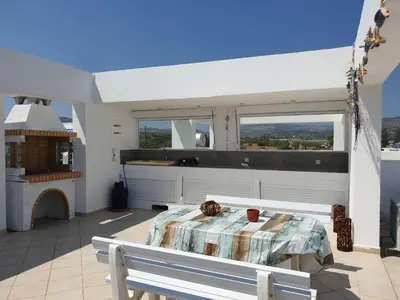 a bedroom with a table and a kitchen with windows at Sea Breeze Villa in Haraki