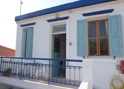 a white house with blue windows and a balcony at Villa Yorgos in Halki