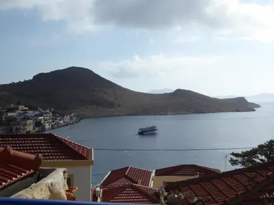 a boat in a large body of water with houses at Villa Yorgos in Halki