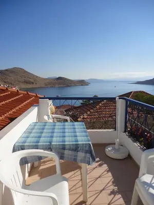 a table and chairs on a balcony with a view of the ocean at Villa Yorgos in Halki