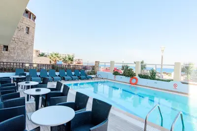 a pool with tables and chairs next to a building at Hotel Riviera in Rhodes Town