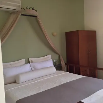 a bedroom with a bed with white sheets and a dresser at Fiore di Flora in Archangelos