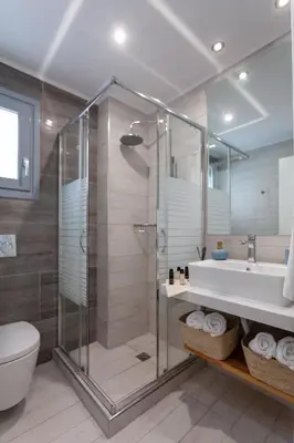 a bathroom with a shower and a sink and a toilet at Luxury Sunrise White Villa in Líndos