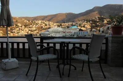 a table and chairs on a balcony overlooking a city at Odyssia in Symi