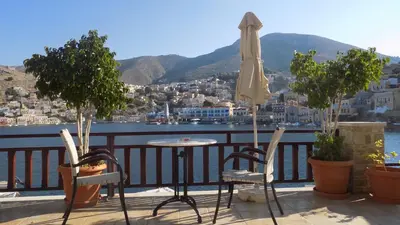 a patio with a table and chairs and an umbrella at Odyssia in Symi