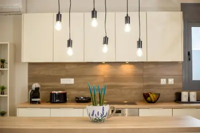 a kitchen with white cabinets and a table with a vase at The Sisters Villa in Kalithies