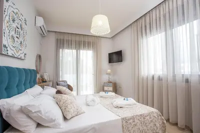 a bedroom with a white bed with a blue headboard at The Sisters Villa in Kalithies