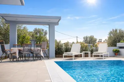 a patio with a table and chairs next to a swimming pool at The Sisters Villa in Kalithies