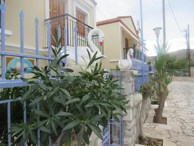 two swans on a fence in front of a building at Chryssa Rooms in Symi