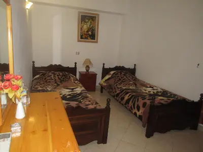a bedroom with two beds and a wooden table at Chryssa Rooms in Symi