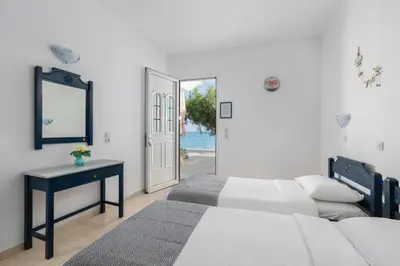 a bedroom with a bed and a table and a door at Kozas Superior Apartments in Archangelos