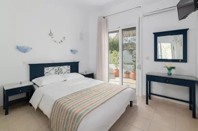 a white bedroom with a bed and a window at Kozas Superior Apartments in Archangelos