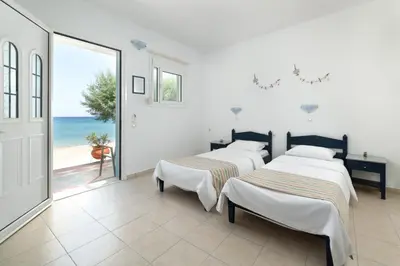 two beds in a room with a view of the ocean at Kozas Superior Apartments in Archangelos