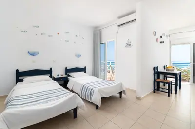 two beds in a room with a view of the ocean at Kozas Superior Apartments in Archangelos