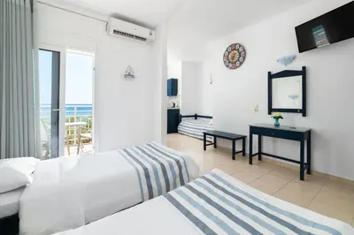 a bedroom with a bed and a desk and a balcony at Kozas Superior Apartments in Archangelos