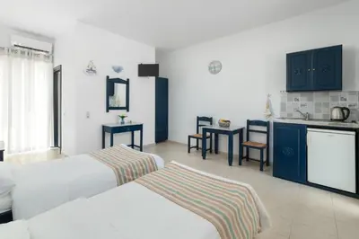 a hotel room with two beds and a kitchen at Kozas Superior Apartments in Archangelos