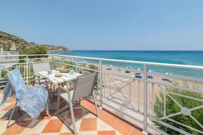 a balcony with a table and chairs and the ocean at Kozas Superior Apartments in Archangelos