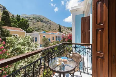 a table and chairs on a balcony with a view at The Old Symi in Symi