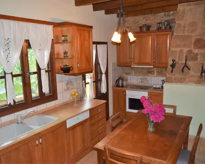 a kitchen with wooden cabinets and a table with flowers on it at Petrino in Rhodes Town